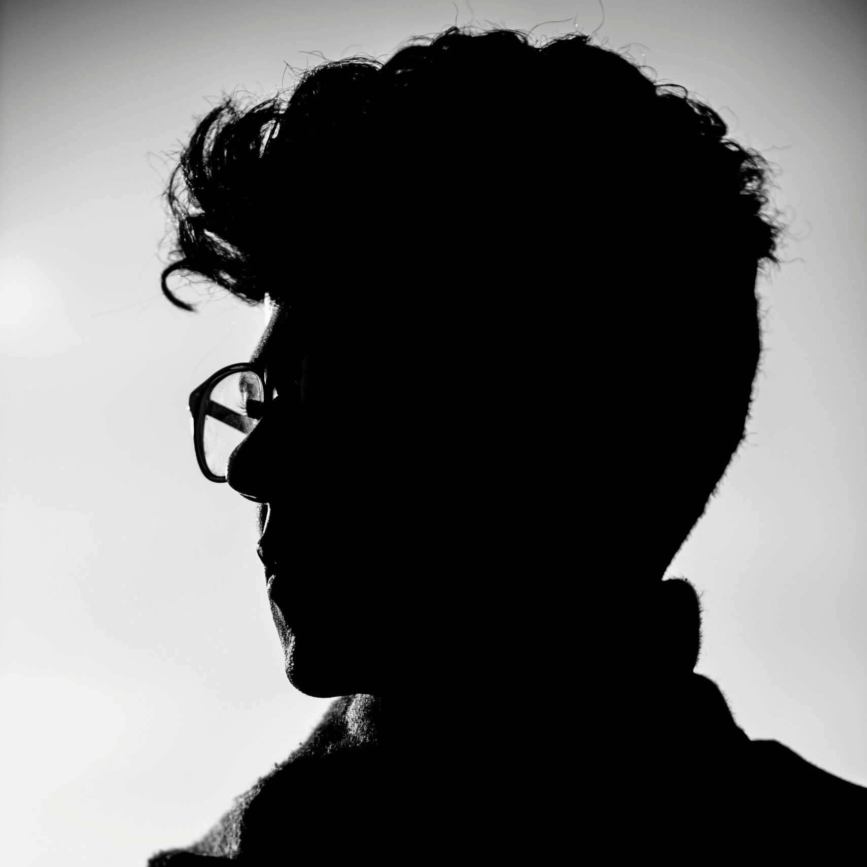 Artistic black and white profile silhouette of a man wearing eyeglasses.